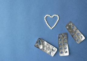 hjärta symbol tillverkad från piller och tabletter blåsa på en blå bakgrund med kopia Plats. preventivmedel och kvinnors hälsa begrepp. kreativ aning för uppkopplad apotek och farmaceutisk företag företag. foto