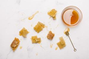 glasburk full honung med honungssked på vit bakgrund