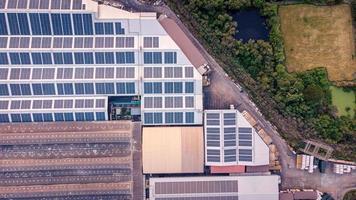 en stor sol- cell tak på ett industriell byggnad alstrande elektricitet för de växt under dagtid enligt till politik och åtgärder till minska global uppvärmningen förbi tar hög-vinkel skott från drönare foto