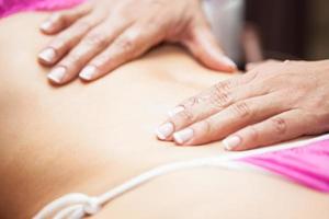 läkare utför ett abdominal massage på en ung kvinna patient foto