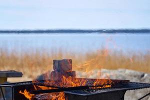 eld i en rostig vintage grill utomhus på stranden av havet foto