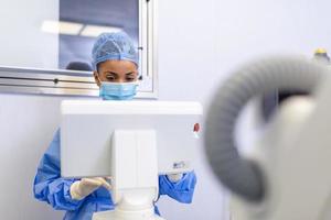 kvinna kirurg med kirurgisk mask på rörelse rum använder sig av 3d bild guidad kirurgi maskin foto