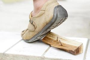 närbild man bär skor är stepping på rostig metall nagel på trä. begrepp, osäker , risk för farlig stelkramp. vara försiktig och se runt om under gående på konstruktion webbplats eller risk platser. foto