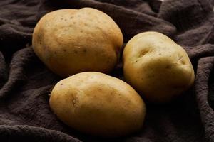 stänga upp rå tre potatis på brun tyg. mat begrepp bakgrund foto