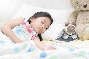 söt liten asiatisk flicka sömn på säng. foto