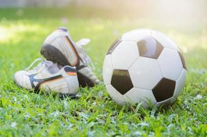 fotboll på grön gräs och hingst sko med Sol ljus foto