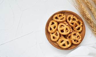 topp se eller platt lägga mini saltade pretzel i en trä- tallrik på vit tabell bakgrund. foto