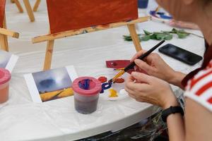 närbild av kvinnlig konstnär hand måla en bild på en palett på verkstaden