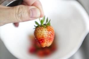 hand som håller jordgubben på vit bakgrund foto