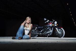 sexig blondin sitter nära hennes motorcykel foto