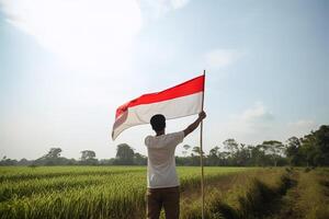 en man innehav en röd och vit indonesien flagga på topp av en frodig grön ris fält. ai genererad foto