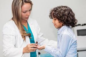läkare ger en barn homeopatisk medicin foto