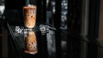 närbild glas iskaffe med mjölk på bordet foto