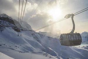 kabel- bilar rör på sig över snö täckt bergen med himmel foto