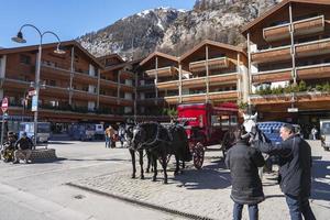 turister stående förbi häst vagn utanför chalet byggnad i stad foto