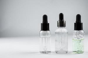 tre glas flaskor av kosmetisk serum på en ljus bakgrund foto