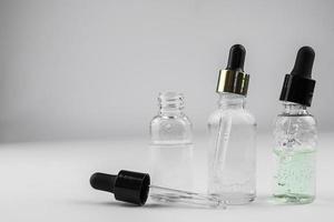 tre glas flaskor av kosmetisk serum på en ljus bakgrund foto