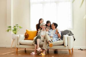 Lycklig familj asiatisk familj, föräldrar och barn Lycklig Sammanträde på de soffa i de hus. de familj slappnar av på de soffa i de levande rum. Lycklig familj foto