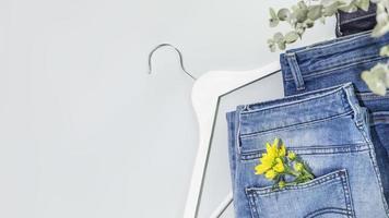 jeans med blomma och galge på blå bakgrund med kopia Plats foto