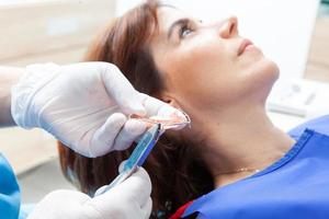 ortodontisk specialist tandläkare justeras en hållare för en kvinna patient foto