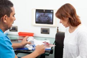 skön kvinna tar emot förklaringar handla om henne dental behandling med henne tandläkare foto