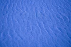 blå bakgrund med sand i de form av sand vågor foto