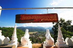 skön vit pagod och lejon skulptur med blå himmel belägen längs de klippa på de berg i phra den där doi kong mu tempel på meahongson provins, thailand foto