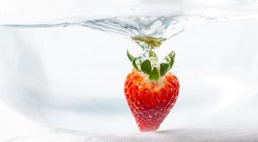 jordgubbar dunked i vatten foto