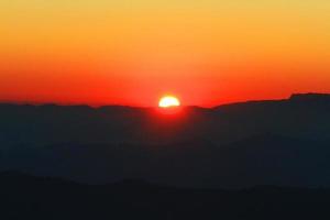 solnedgång i himmel och moln, skön färgrik skymning tid med silhuett av berg. foto