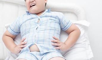 fet pojke övervikt magont på säng foto