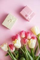 rosa och gul tulpan blommor, gåva lådor är anordnad på en rosa bakgrund. de se från de topp. de begrepp av vår. kvinnors dag. foto