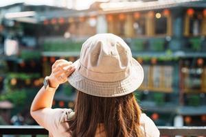 kvinna resande besöker i taiwan, turist med hatt och ryggsäck sightseeing i jiufen gammal gata by med te hus bakgrund. landmärke och populär attraktioner nära taipei stad. resa begrepp foto