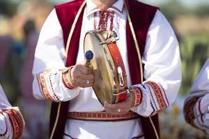 en musiker i broderi spelar ett etnisk trumma. foto