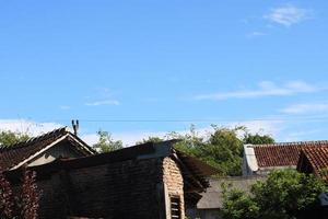 Foto av de blå himmel ovan de tak plattor av de hus