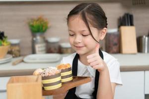 porträtt av en liten flicka i de kök av en hus har roligt spelar bakning bröd foto