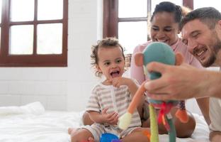 föräldrar med liten flicka ha roligt spelar med din ny leksaker i de sovrum tillsammans. leksaker den där förbättra barns tänkande Kompetens. foto