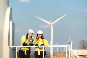 man och kvinna ingenjör stationerad på de naturlig energi vind turbin webbplats. med dagligen granska uppgifter av större vind turbin operationer den där omvandla vind energi in i elektrisk elektricitet foto