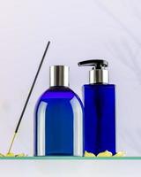 blå kosmetisk flaskor på glas hylla på ljus lutning bakgrund foto