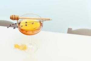 honung i glas glas, lavendel- kvistar och honung dipper på vit tabell foto