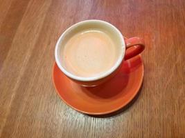 orange kopp av kaffe på en trä- tabell. kaffe i en kopp foto