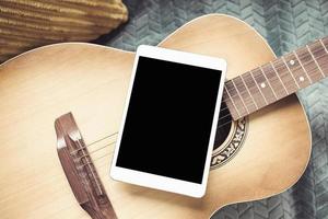 akustisk gitarr och digital läsplatta på en soffa foto