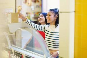 Lycklig asiatisk kvinna uppköp is grädde foto