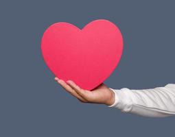 ett hand innehav röd hjärta isolerat på enkel bakgrund. foto