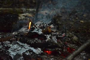 lysande glöd i varm röd Färg. de varm glöd av brinnande trä logga brand. ved brinnande på grill. textur bål glöd. grå och röd glöd abstrakt bakgrund. foto