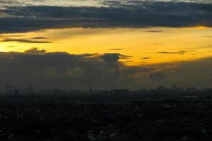 solnedgång i de förorter av jakarta, var de himmel börjar till se gul och du kan ser de silhuetter av flera lång byggnader foto