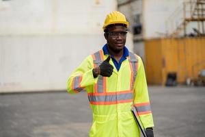 arbetstagare man i skyddande säkerhet overall enhetlig med gul hårdhatt.arbetare i fabrik som visar tummen upp foto