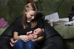 ung mor med en gråt nyfödd bebis. foto