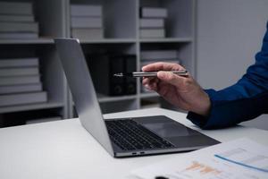 stänga upp se av affärsman använder sig av bärbar dator dator på kontor skrivbord i de kontor rum. foto