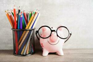 pigging bank bär glasögon med mynt och miniräknare spara bank utbildning koncept. foto