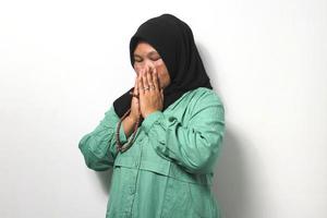 mitten åldrig asiatisk kvinnor bär hijab ber till Gud och innehav bön pärlor isolerat över vit bakgrund. foto